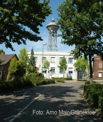 Verwaltungsgebäude mit Wasserturm und Pförtnerhäuschen (r.)